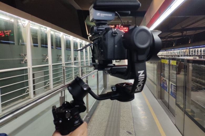 Camera being held with a gimbal filming in a train station